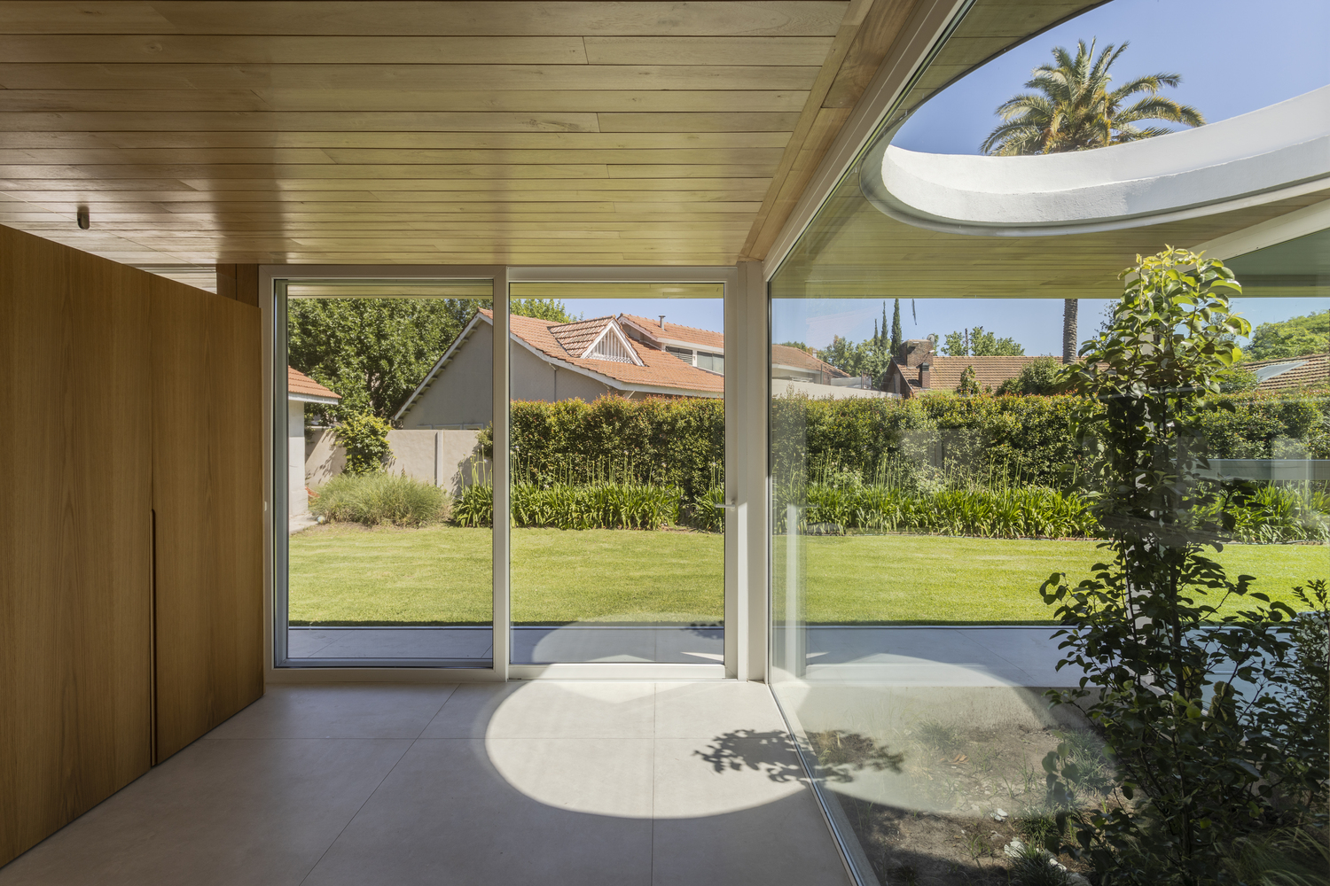 Interior view of living space with circular skylight opening and sliding doors to garden