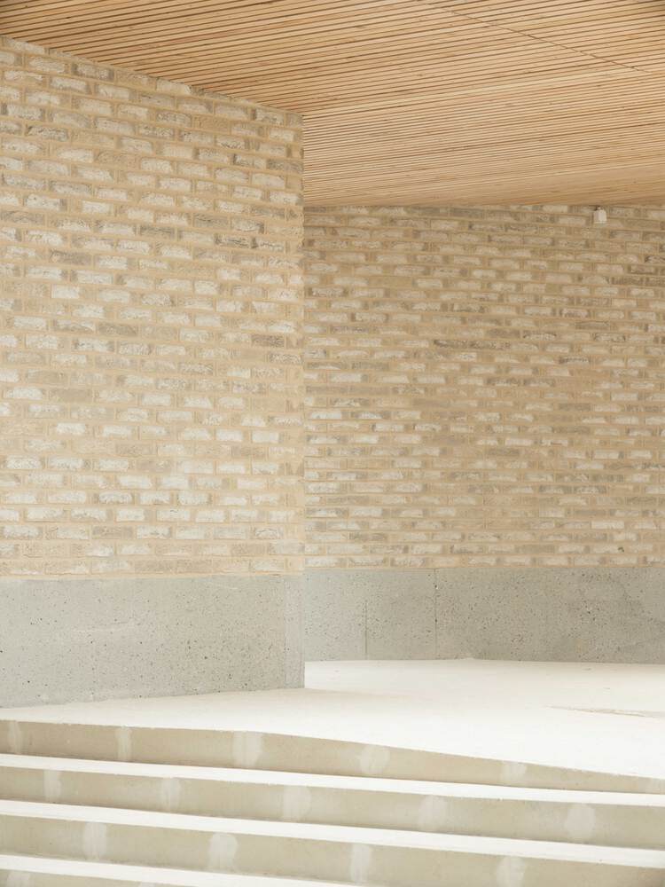 Interior corner showing pale brick walls, timber slat ceiling and terrazzo stairs descending
