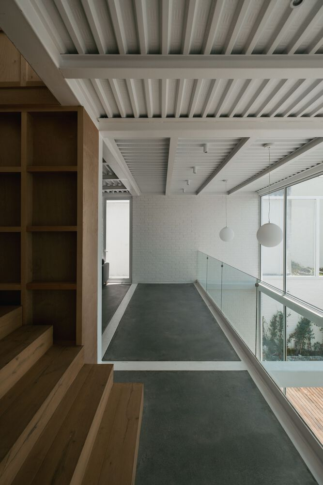Interior hallway with exposed timber beam ceiling and glass railing overlooking the courtyard below