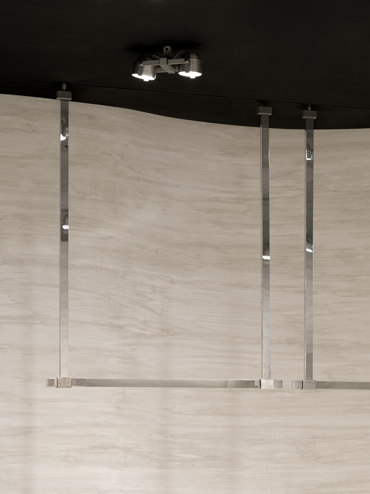 Glass balustrade with metal posts and horizontal rails under a black ceiling with suspended lighting