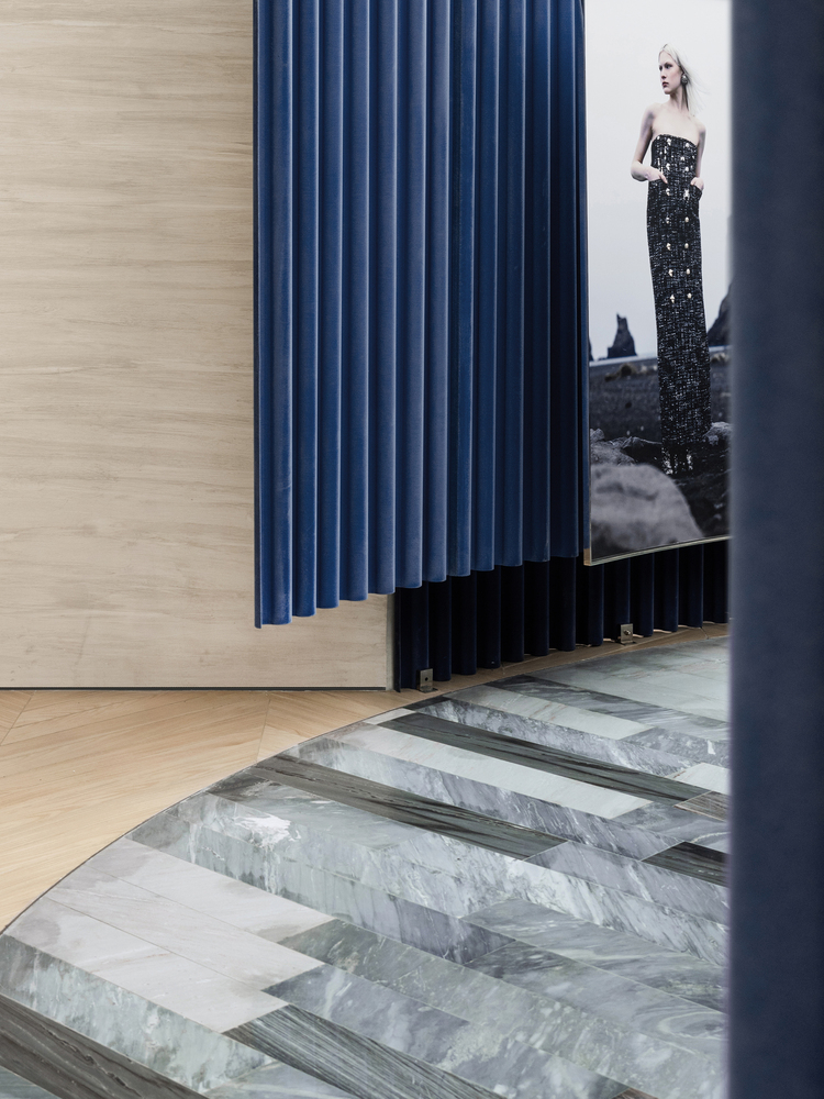 Blue vertical panel radiator beside a doorway with striped marble flooring and fashion photograph beyond