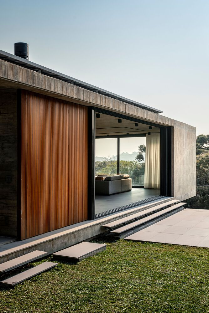 Concrete threshold steps leading to living room framed by vertical timber cladding