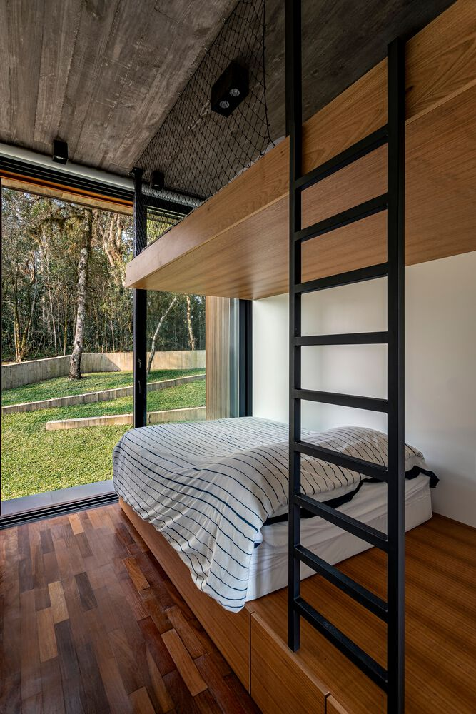 Bedroom with black-framed partition and floor-to-ceiling windows opening to lawn