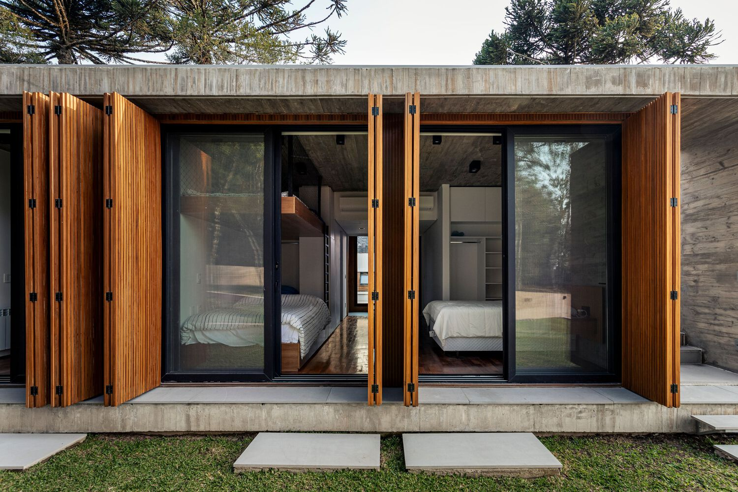 Pair of bedrooms with pivoting timber shutters and glazed doors on concrete base