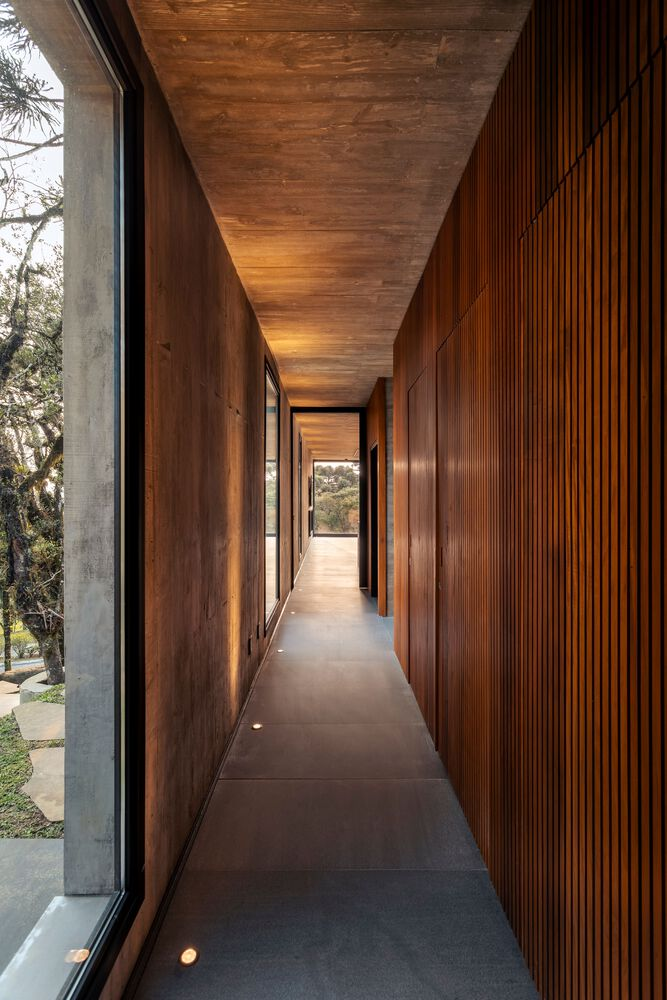 Narrow corridor with vertical timber cladding and wood-clad ceiling lit by low wall-mounted fixtures