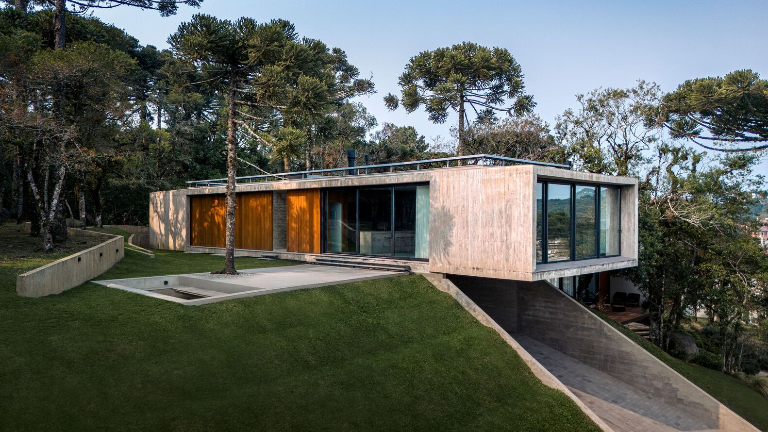 Staggered concrete volumes with timber-clad facades and a green roof terrace among pine trees