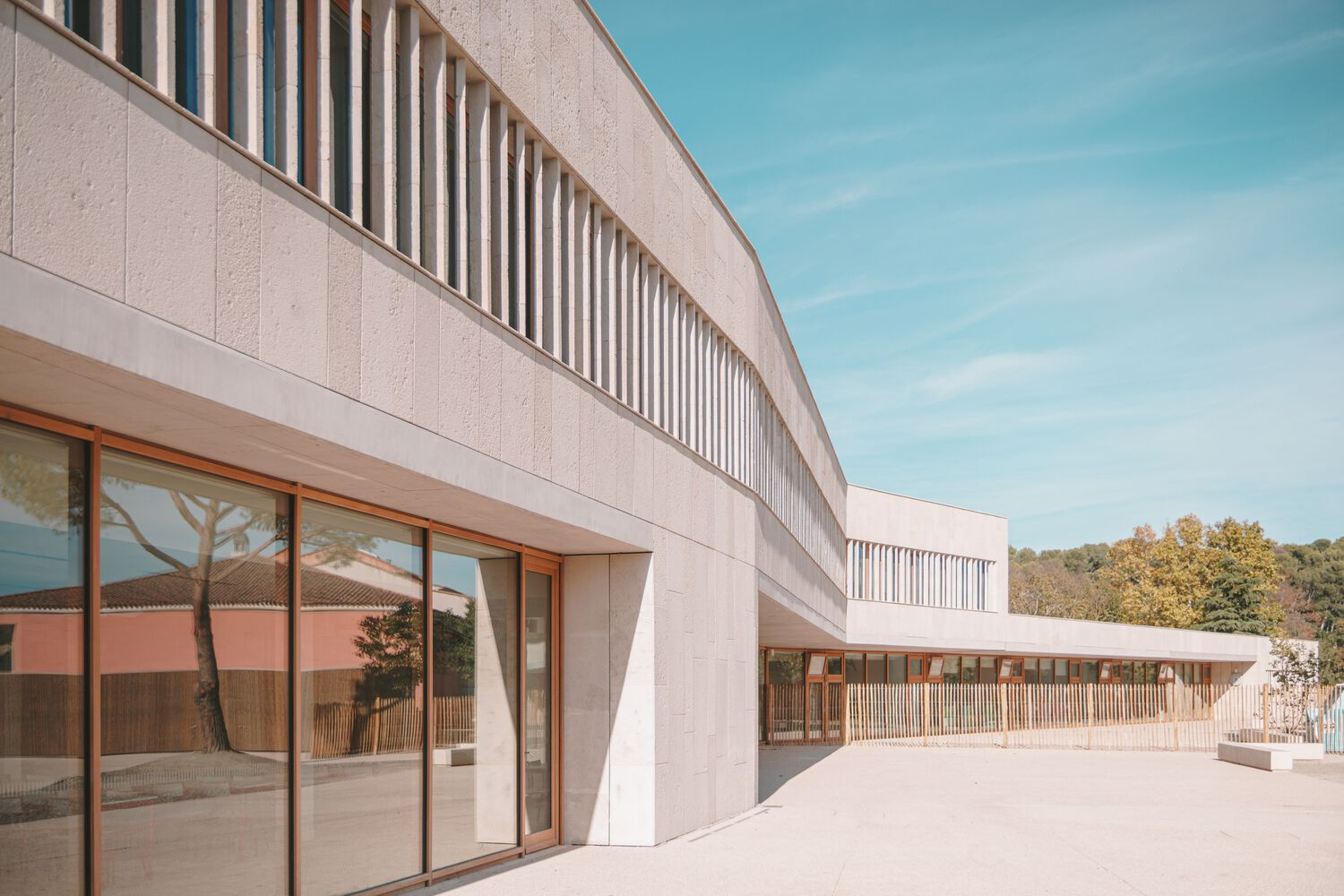 Curving two-storey facade with vertical louvres and sliding glass doors opening to a paved courtyard