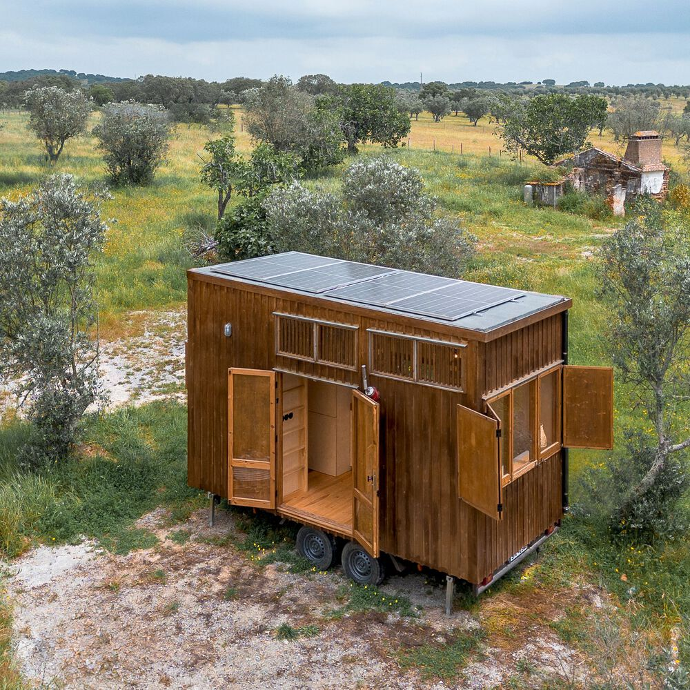 Aerial view of the cabin with solar panels on the roof and multiple hinged doors opening