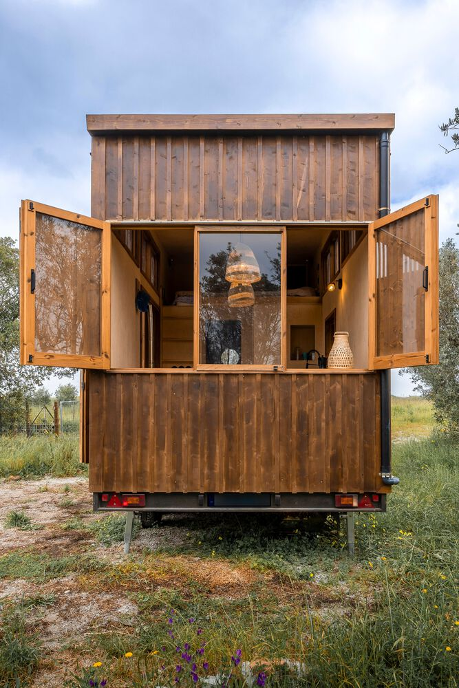Rear facade with hinged timber shutters opening to reveal an upper loft window and trailer undercarriage