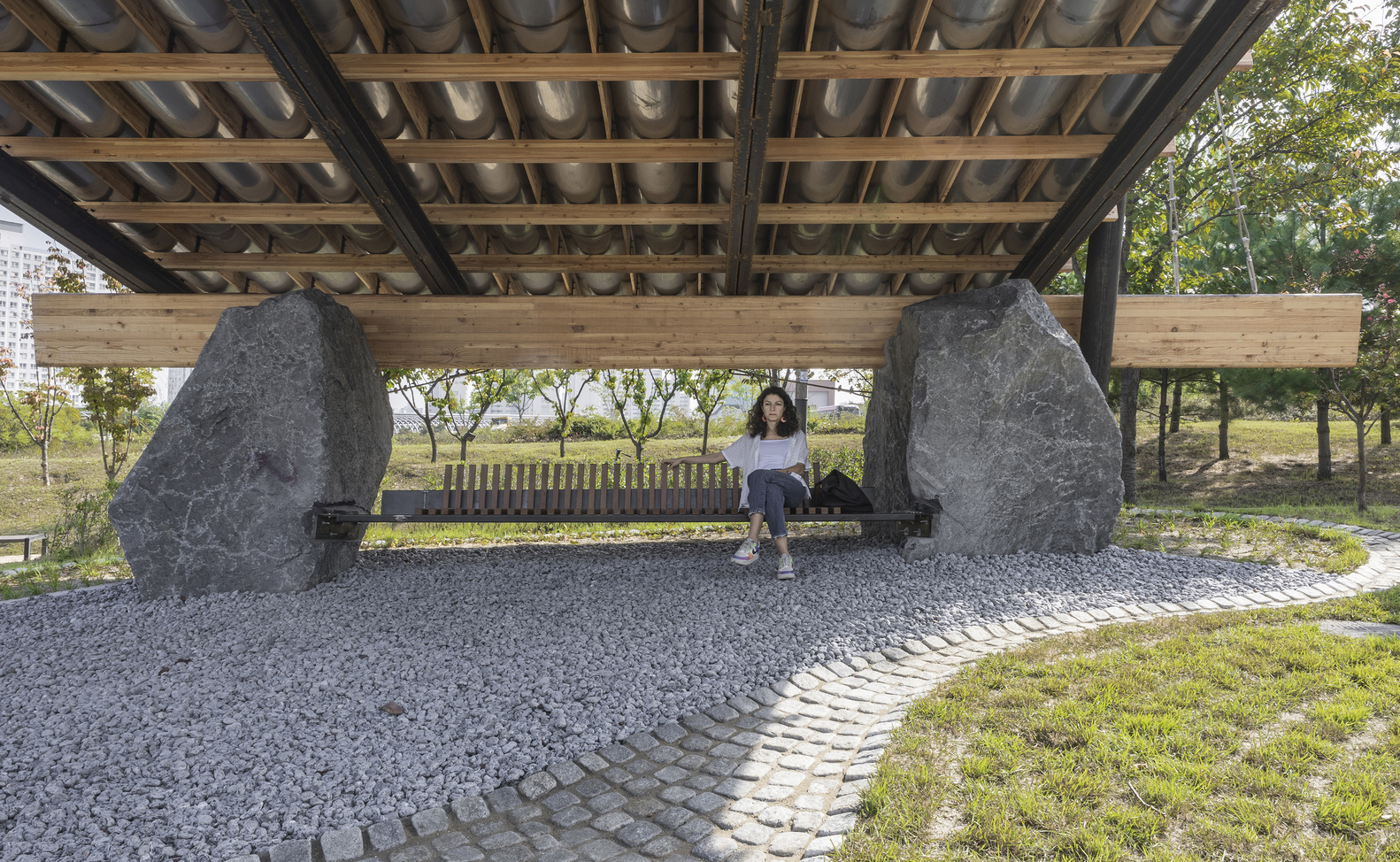 Bench seating between two rough-cut stone supports under the timber and tile roof canopy
