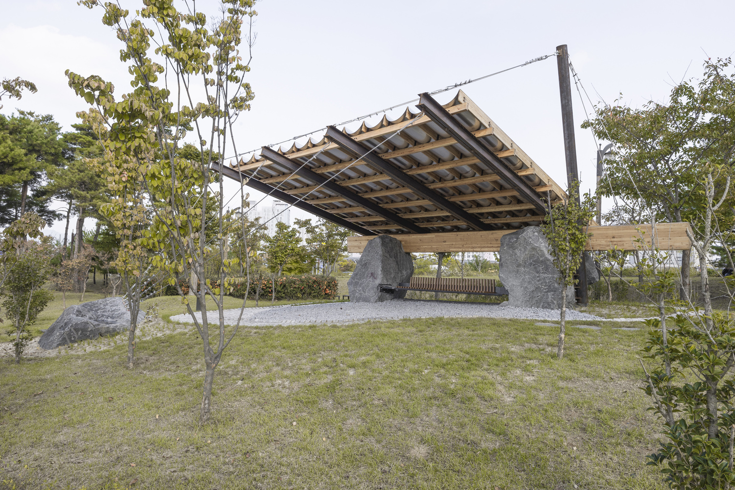 Underside view showing exposed timber joists and corrugated panels above the stone base and lawn