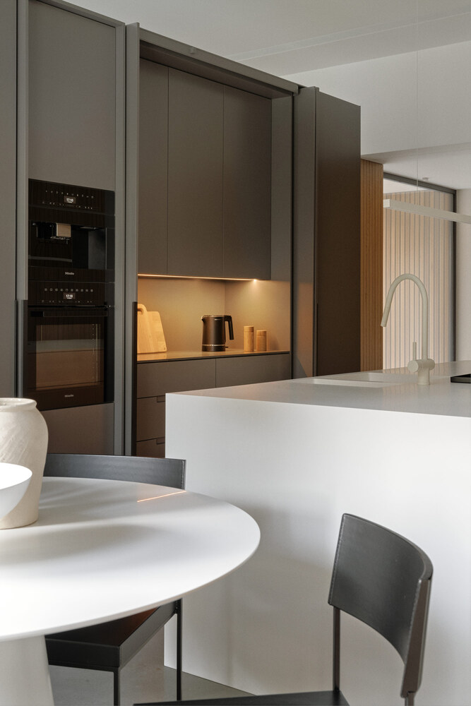 Kitchen view showing dark cabinetry with integrated backlighting and a white marble island with dining table