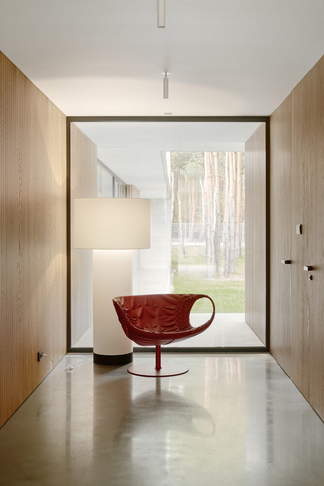 Corridor with timber-clad walls and polished concrete floor framing a view of the forest