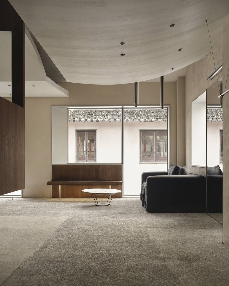 Living area with curved plaster ceiling and floor-to-ceiling windows framing a traditional tiled roof courtyard
