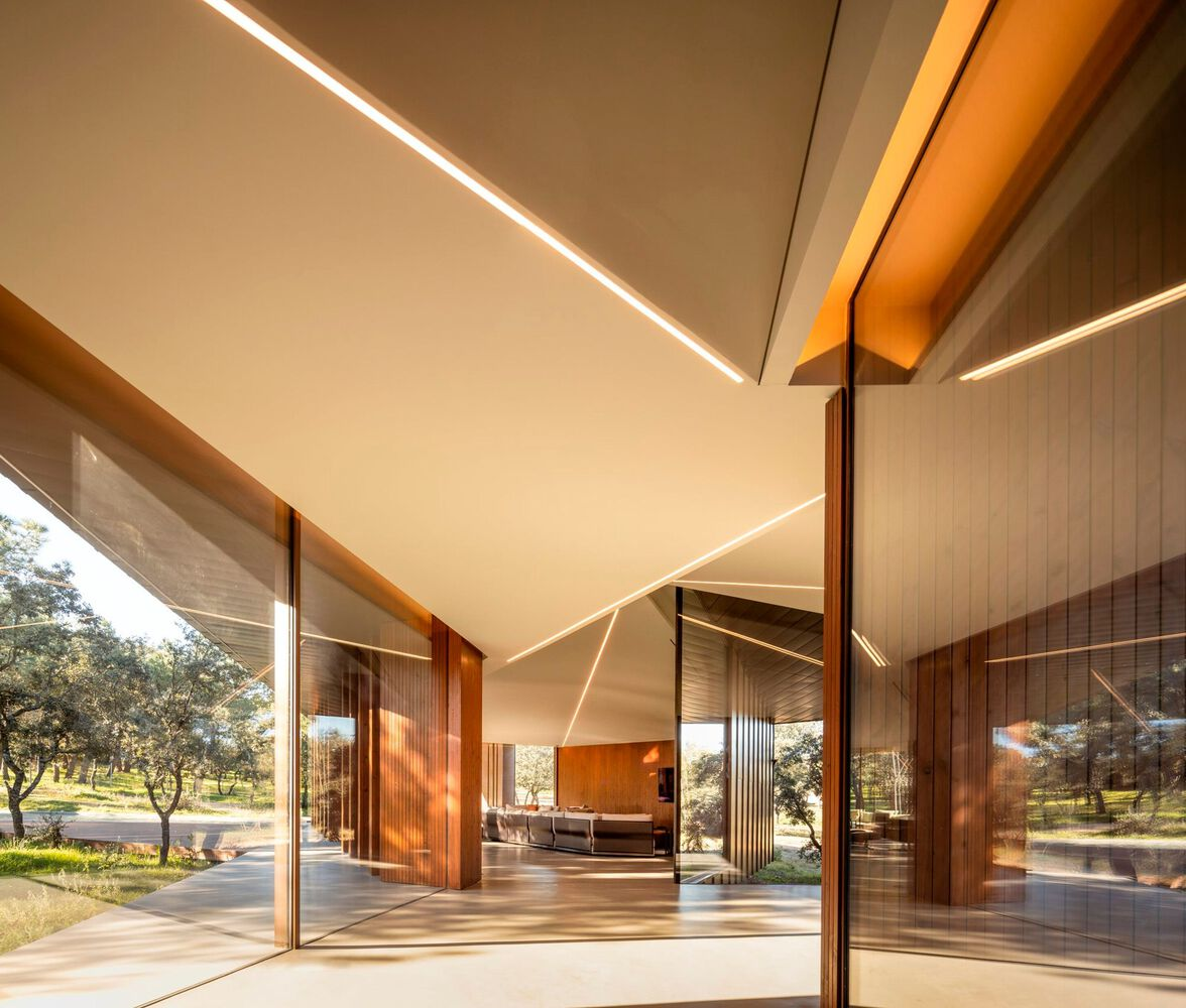 Open glazed corner with sliding timber doors and linear ceiling lighting beneath the angled roof plane
