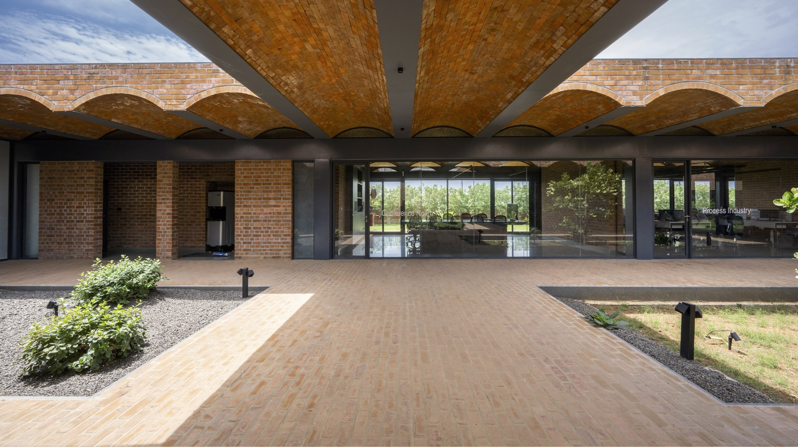 Symmetrical view along brick-paved path beneath radiating vaulted canopy toward glazed interior