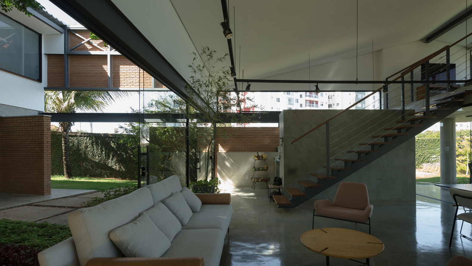 Double-height living space with concrete stair and ceiling framing views to planted courtyard beyond