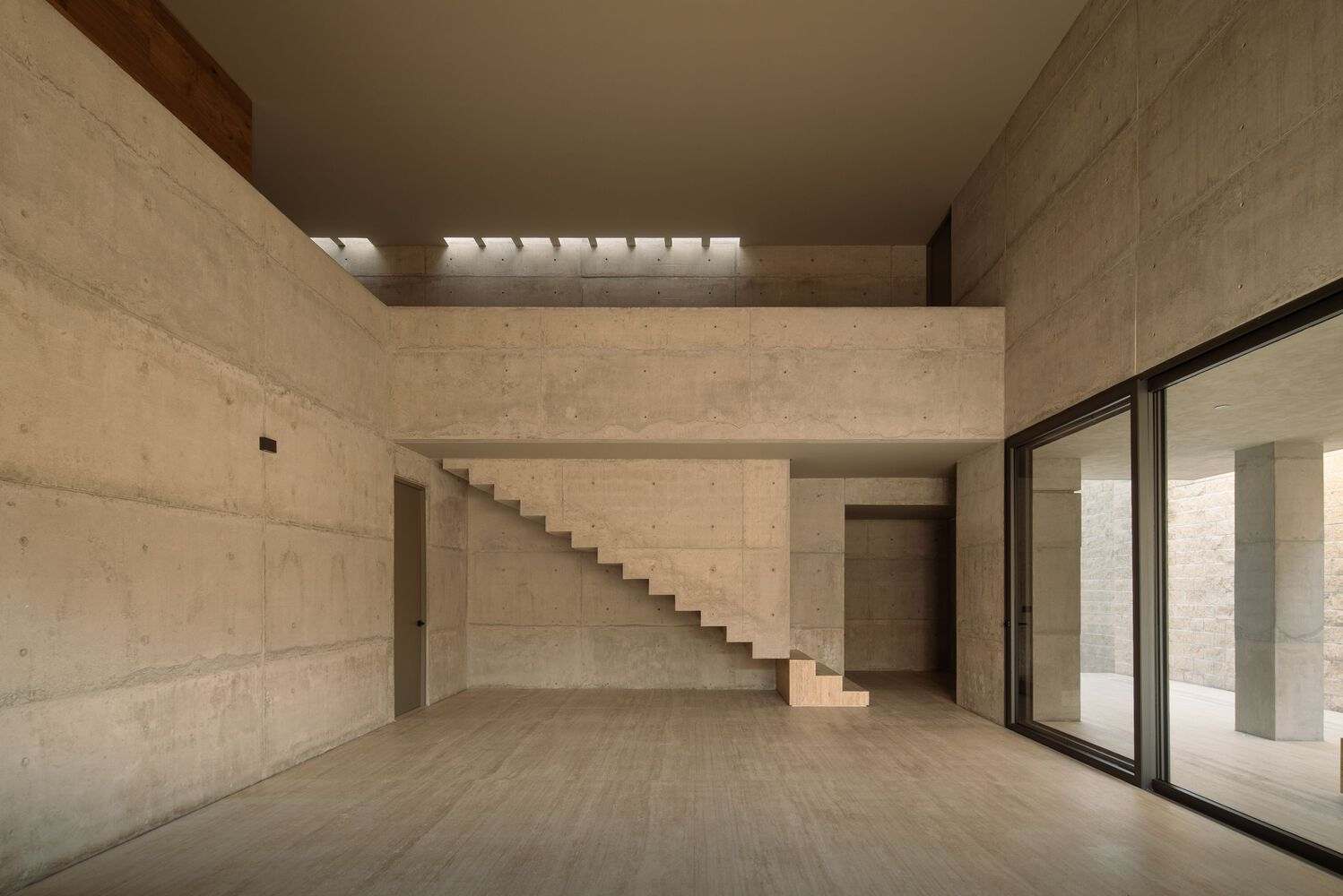Double-height interior space with floating concrete staircase and timber-lined clerestory above