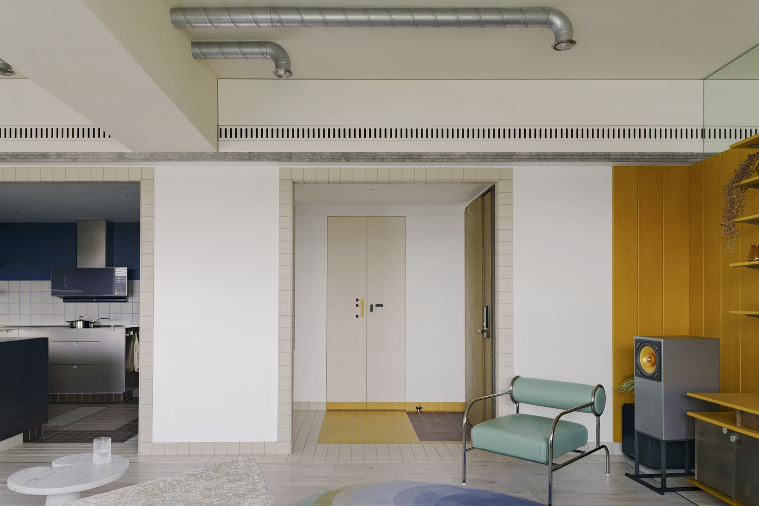 Open living area with exposed ductwork, white tile banding, and yellow millwork framing a doorway