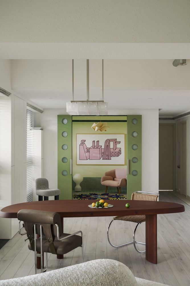 Dining area with pendant lights suspended over a dark wood table and green niche beyond