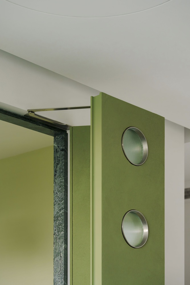 Detail of green wall panel with two circular metal insets and sliding track hardware