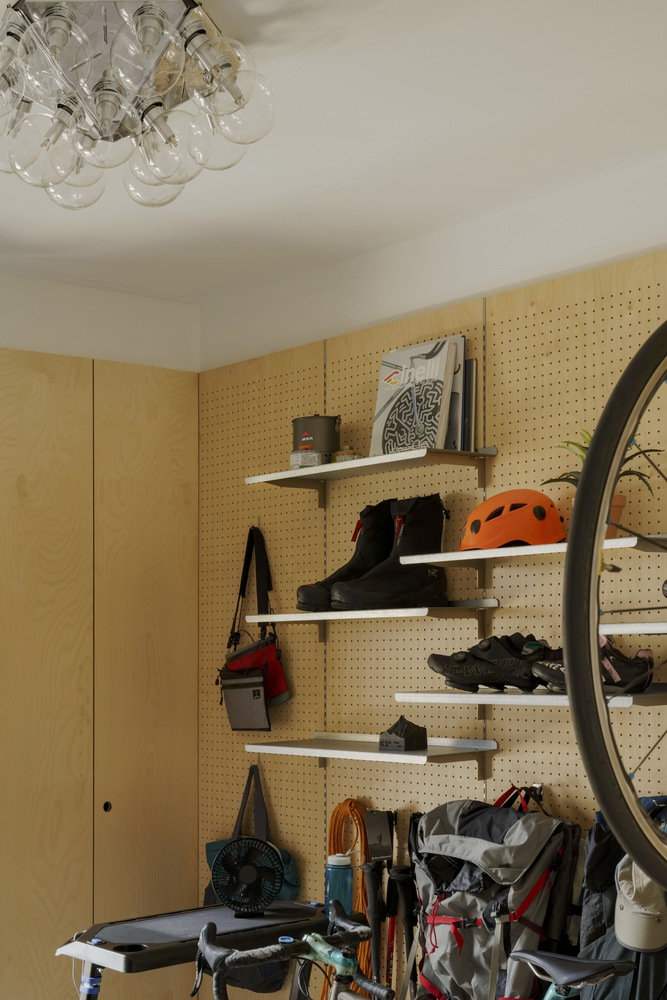 Pegboard wall with shelves holding cycling gear and helmets beneath a cluster of glass globe lights