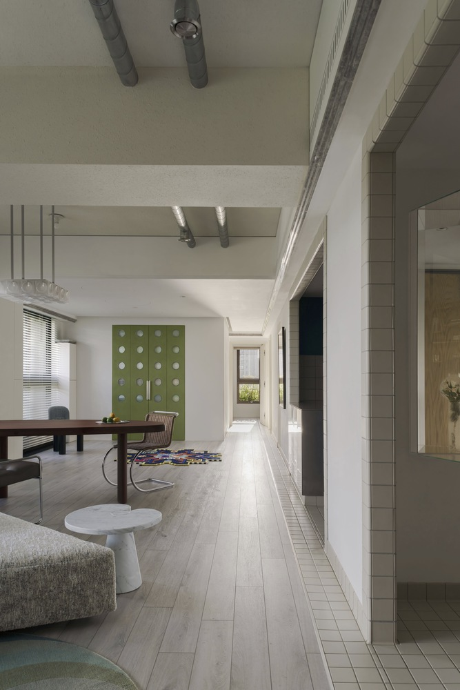 Open interior corridor with exposed ductwork overhead and green paneled partition wall visible down the hallway