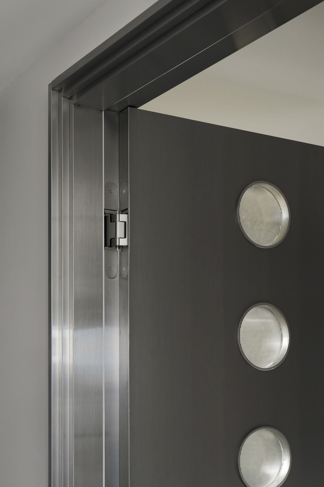 Dark door with three circular reeded glass porthole windows and brushed steel frame