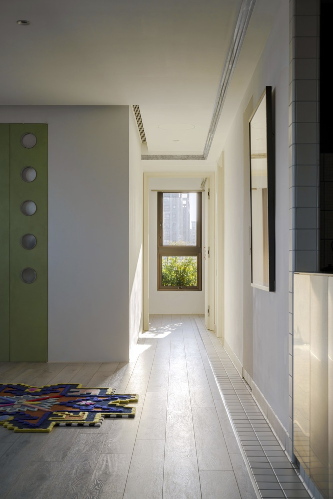 Hallway with skylight above pale wood flooring leading to window overlooking greenery and towers