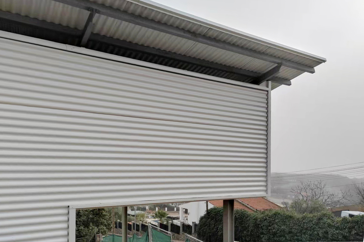 Detail of horizontal corrugated metal roller shutter partially deployed on an overcast day