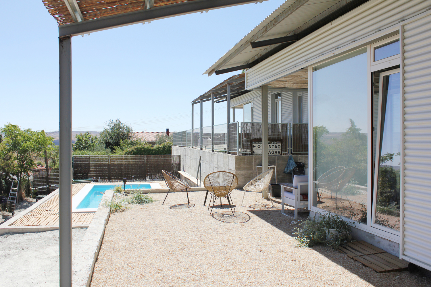 Sequence of timber pergolas along the terrace edge with pool and landscape in the distance