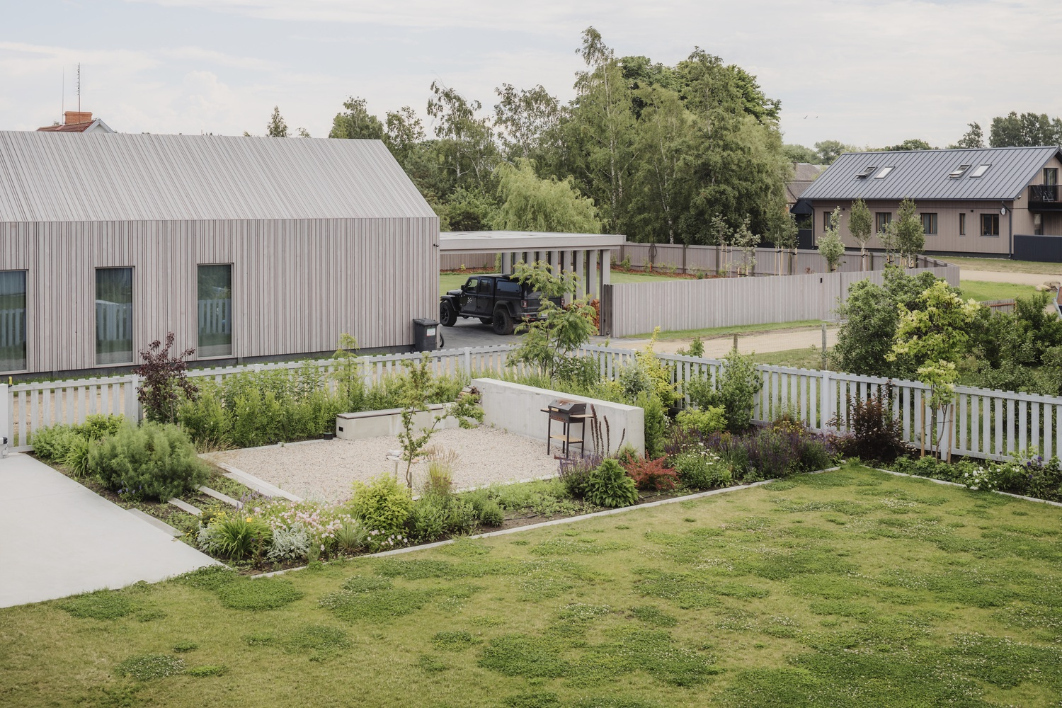 Elevated view of the planted courtyard with gravel paths and white fence with neighboring houses beyond