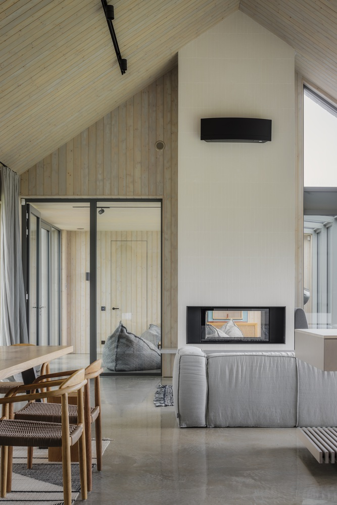 Tall white chimney mass with through-view fireplace opening into the living area with polished concrete floor