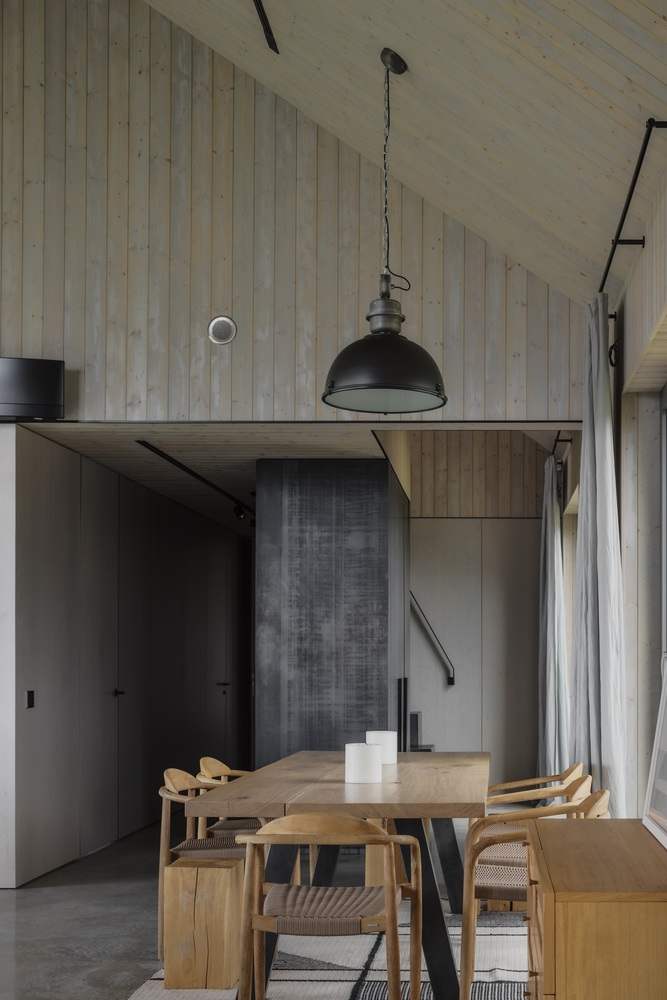 Dining area with charcoal kitchen joinery and vintage pendant hanging from the sloped timber ceiling