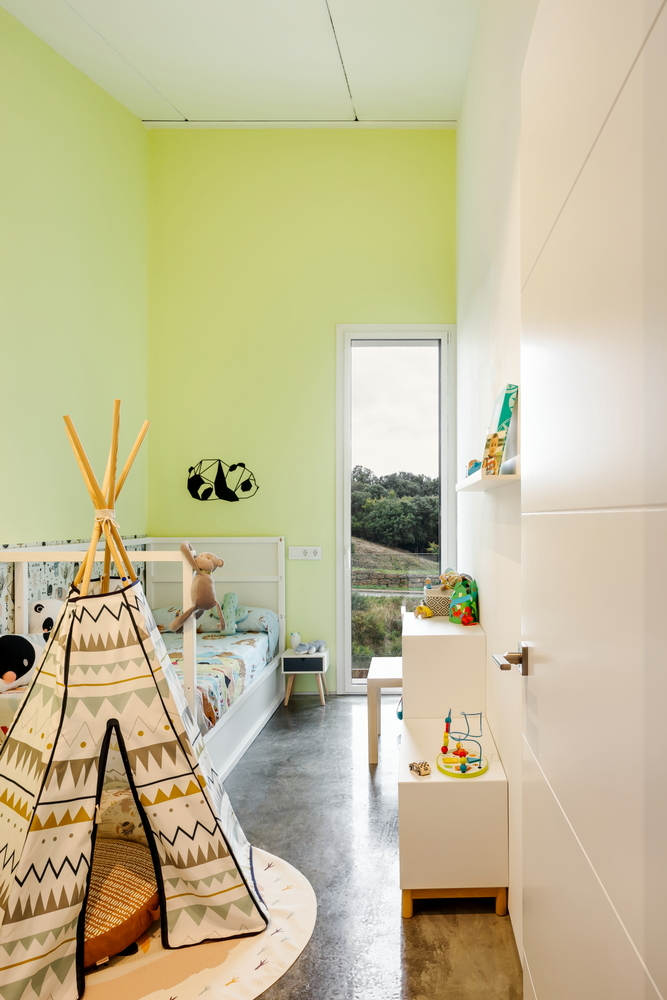 Bedroom with pale yellow wall and vertical window framing treetops