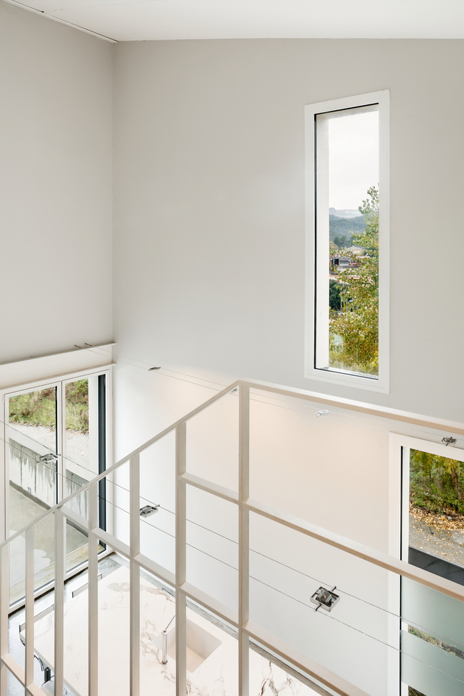 Upper landing with steel railing and tall narrow window overlooking distant landscape
