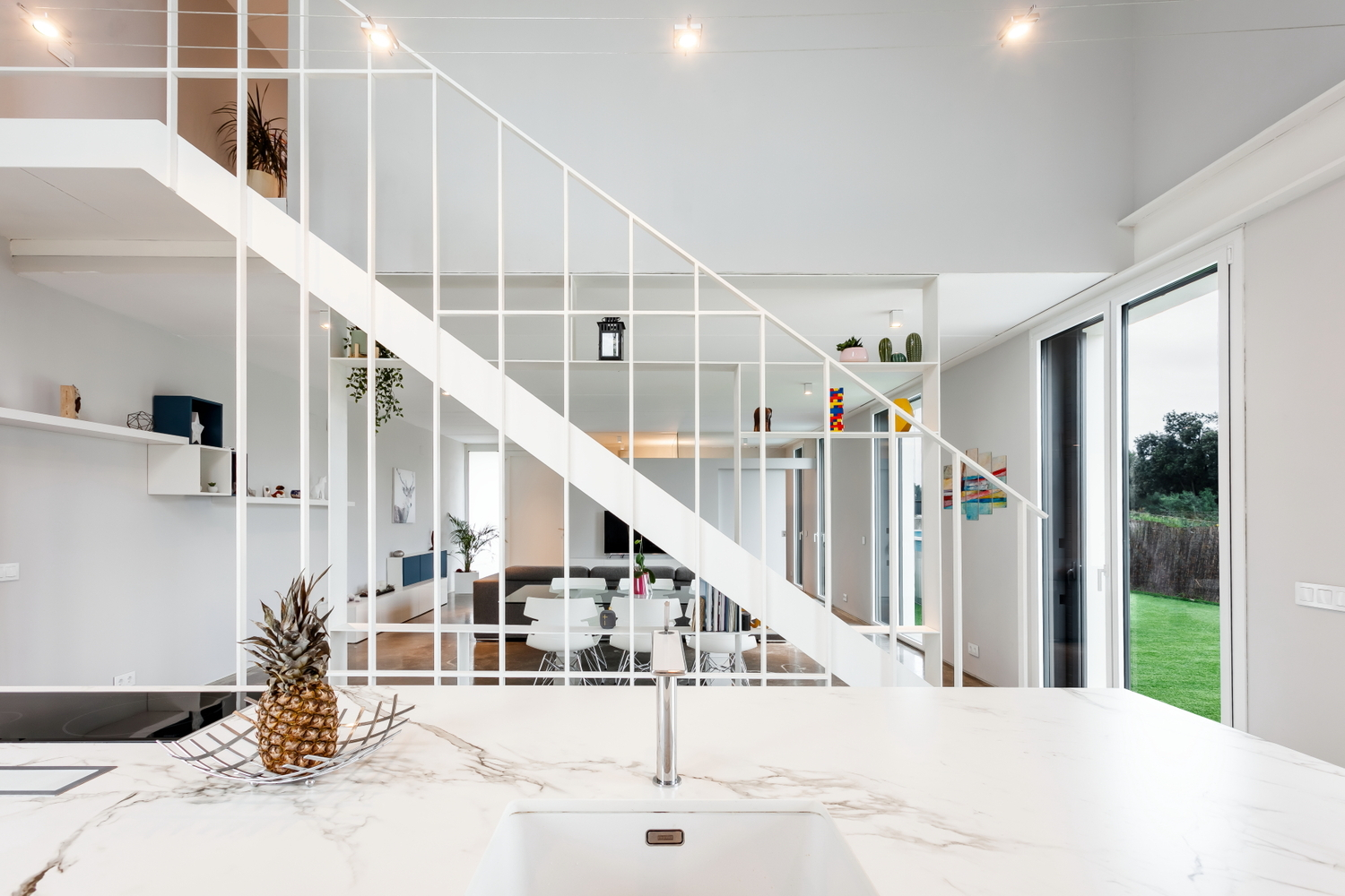 White island counter with marble top looking through the open stair grid toward the lawn outside
