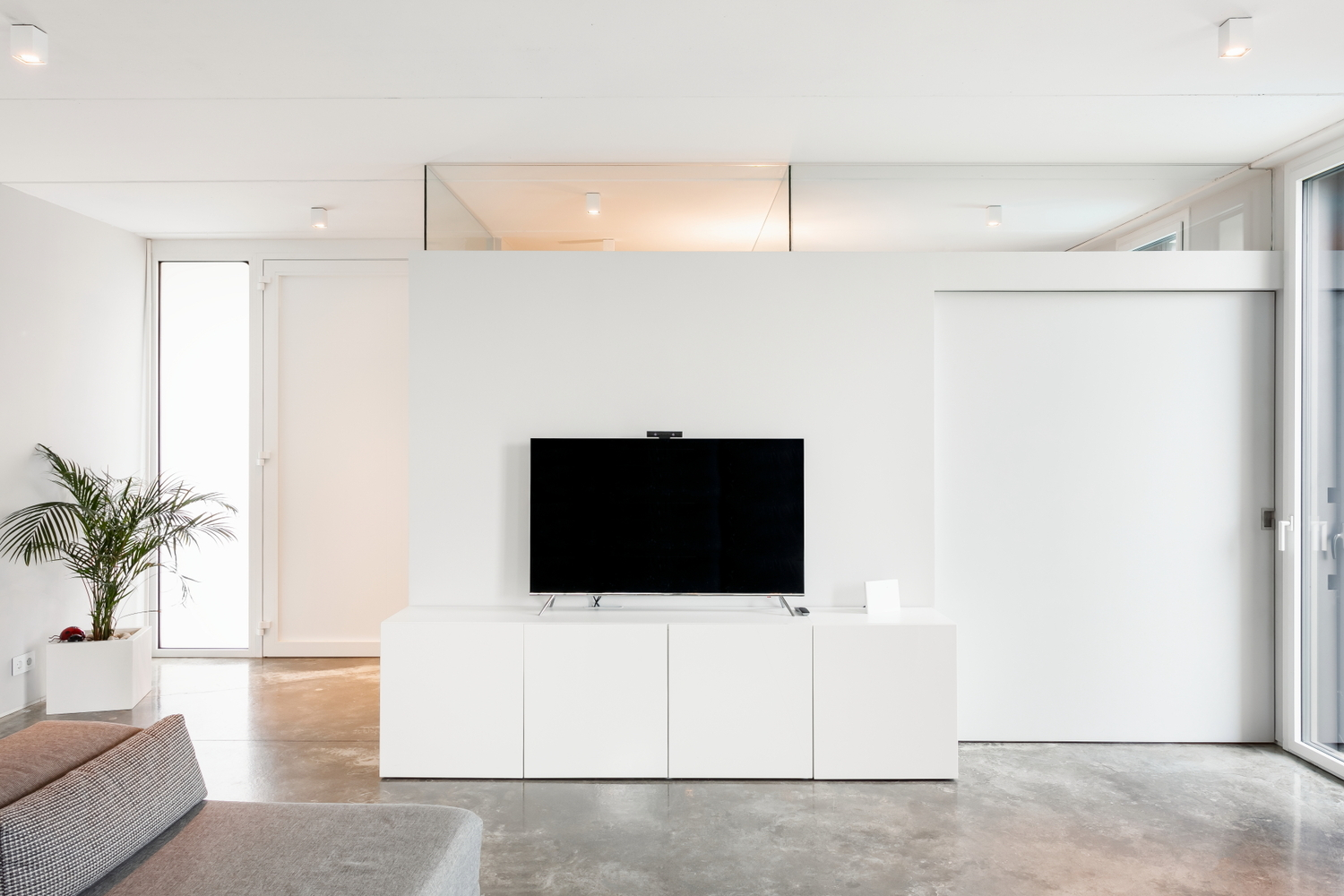 Living area with white media console and polished concrete floor beneath a recessed skylight