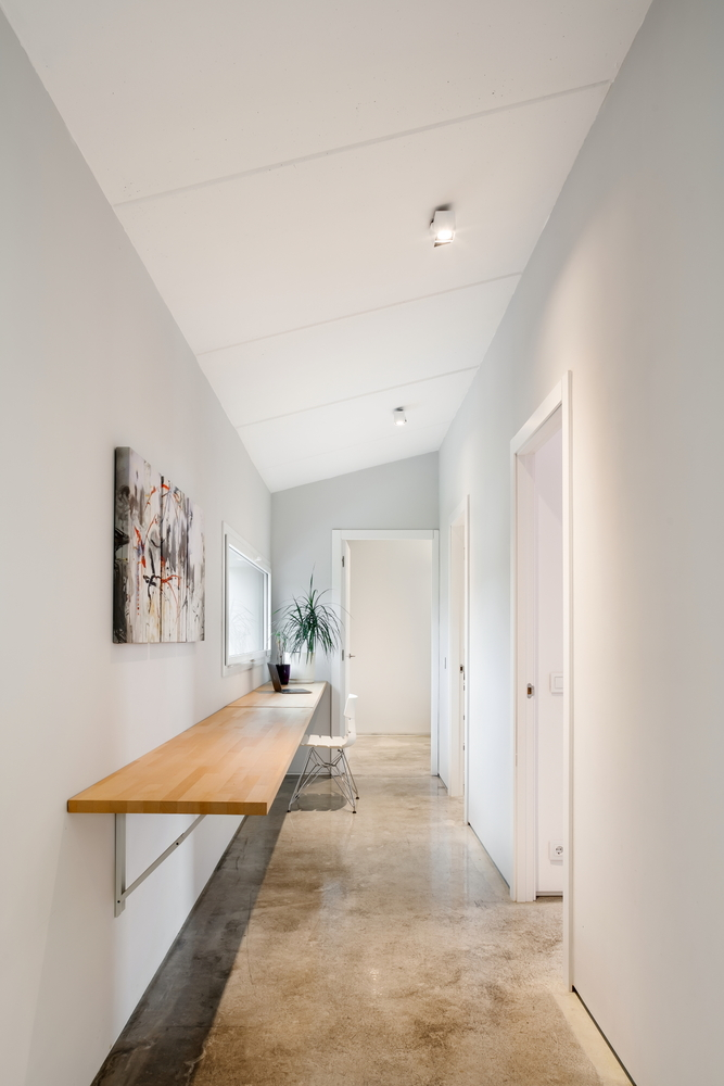 Hallway with wall-mounted timber bench and polished concrete floor under a vaulted ceiling