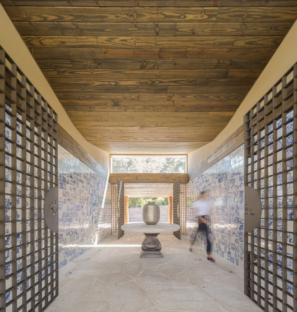 Corridor with timber lattice screens flanking blue-patterned tile walls and a wood plank ceiling