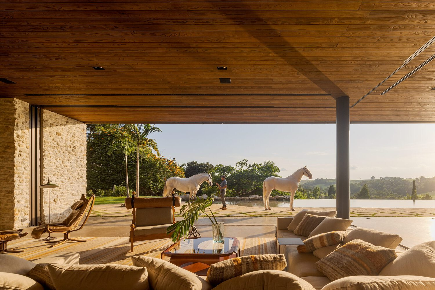 View from the seating area through the open glass wall to horses and handler on the terrace