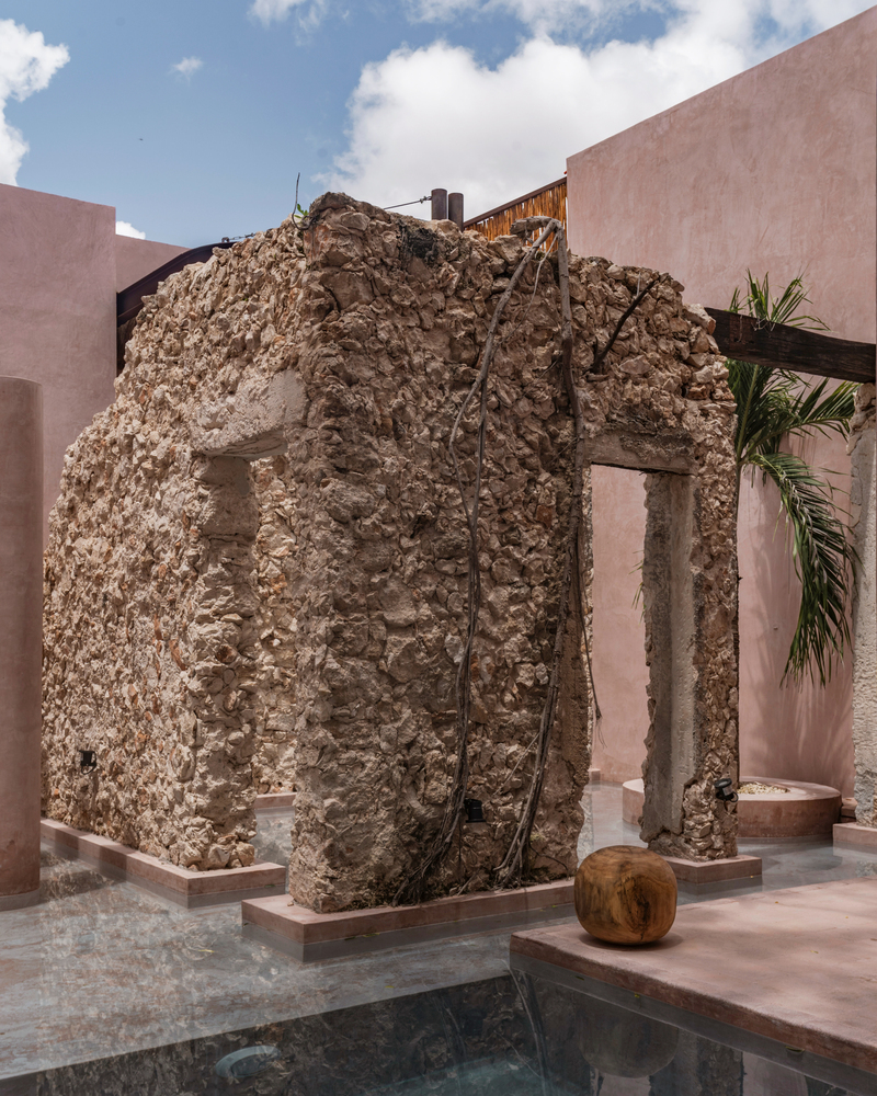 Ancient stone masonry fragment with arched openings integrated beside a reflecting pool