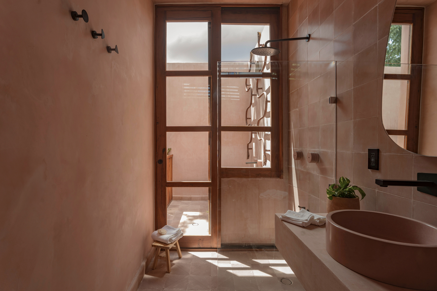 Bathroom with glazed shower door and terracotta vessel sink in morning sunlight