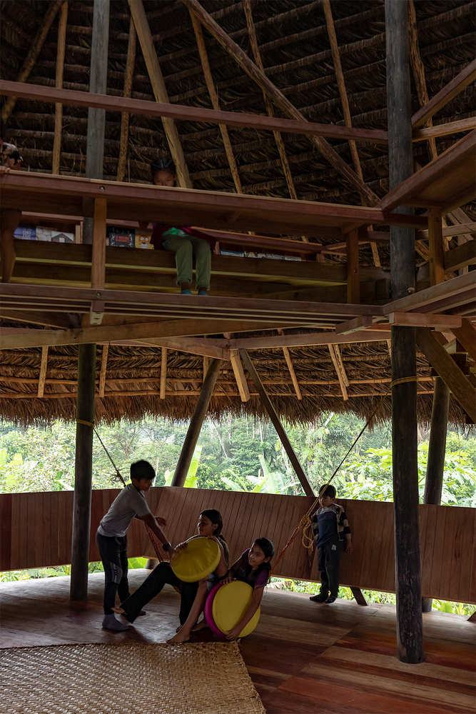 Timber structural frame with exposed rafters and children on swings suspended from an upper platform