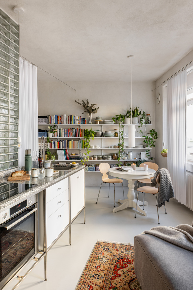 Kitchen and dining area with glass block wall, white shelving, and terrazzo countertop
