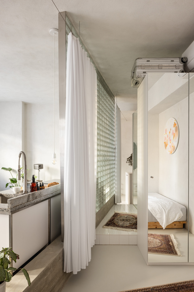 View toward bedroom with glass block window wall behind sheer white curtain and mirrored wardrobe