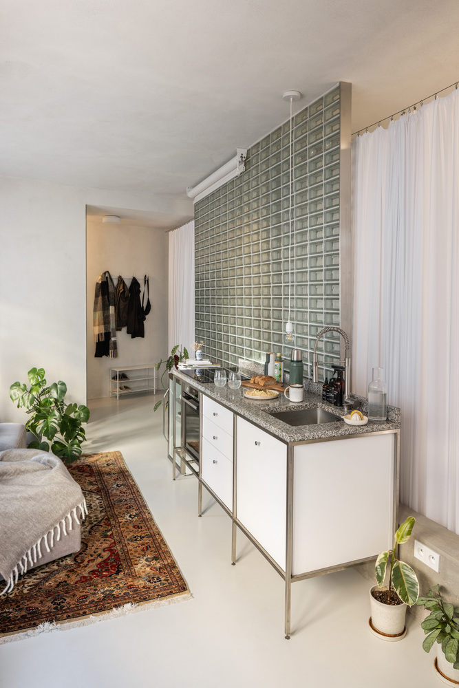 Freestanding kitchen unit with terrazzo countertop and glass block backsplash rising to the ceiling