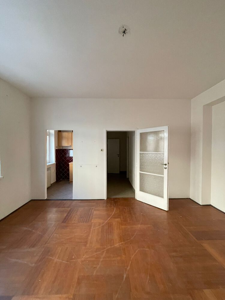 Empty room with herringbone parquet flooring and three doorways leading to adjacent spaces