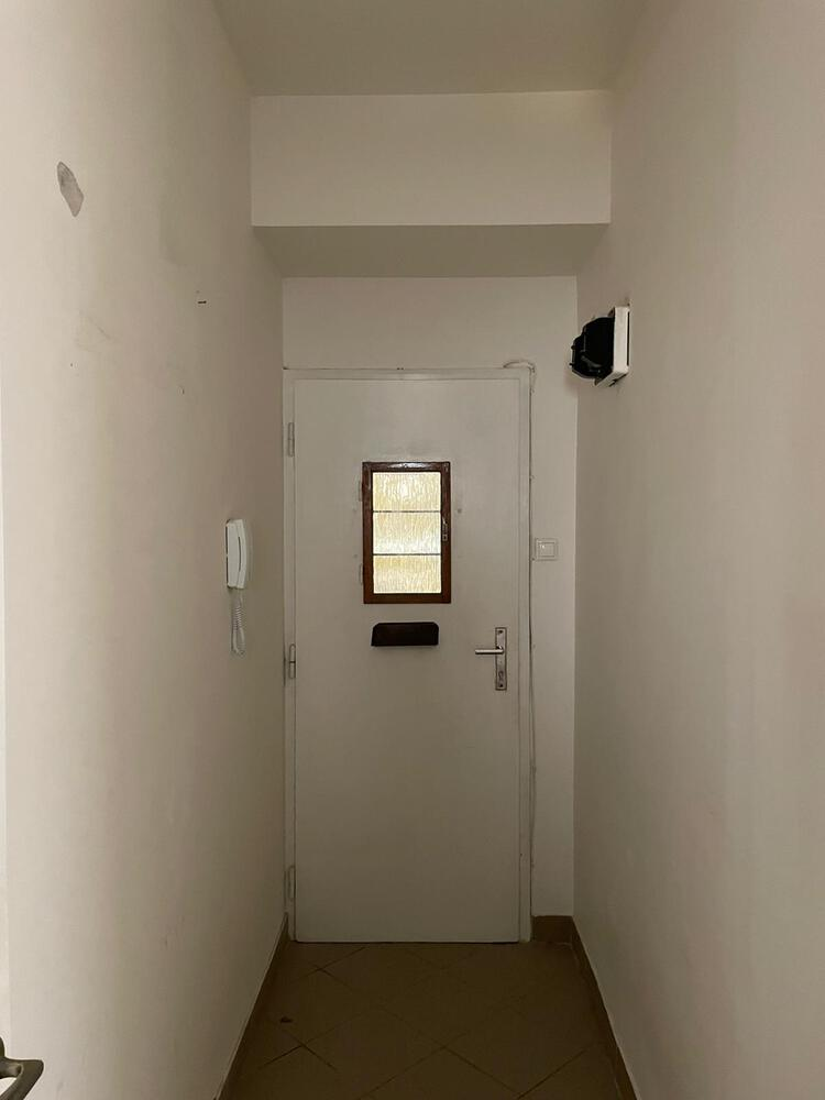 Narrow entry vestibule with white door featuring a frosted glass panel and intercom