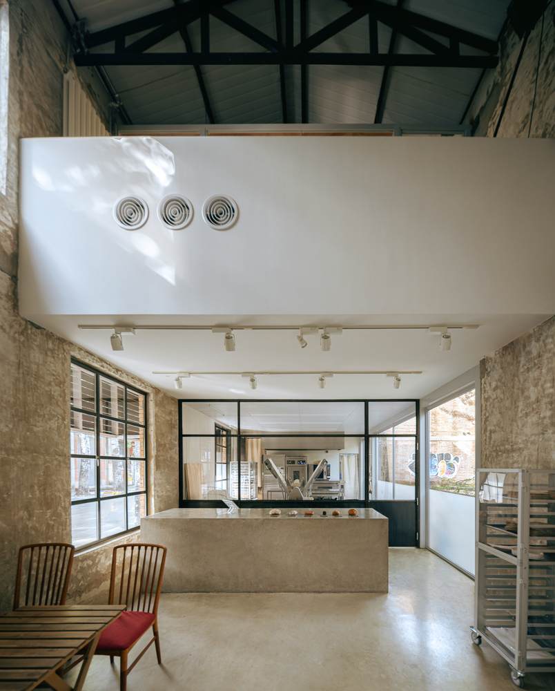 Interior counter with exposed brick walls and black steel truss ceiling under natural light